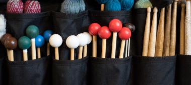 Image of multiple and various colored drumming mallets.